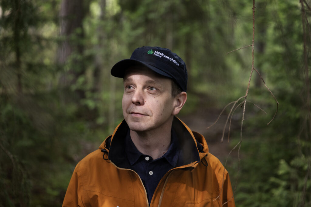 Kuvassa mies oranssissa takissa ja lippalakissa.